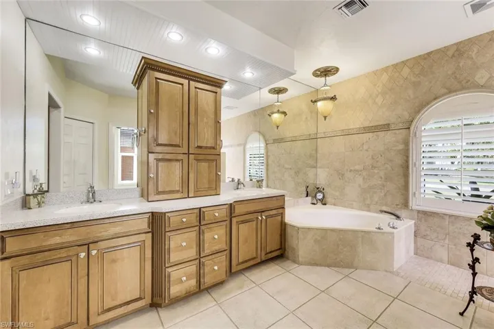 This ensuite bathroom offers separate vanity areas, plenty of storage space, an oversized tub and a walk in shower.