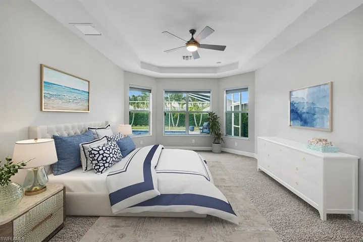 Brand new carpet in primary bedroom with a tray ceiling and bay window overlooking pool area. This room has been virtual staged.