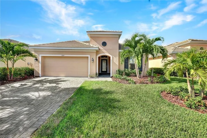 Mediterranean style home featuring a two-car garage, tile roof built in 2018 with a well maintain landscaping, and paver driveway.