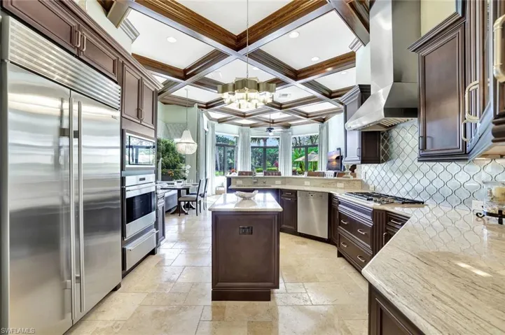 Kitchen with coffered ceiling, dark brown cabinetry, built in appliances, a peninsula, and beam ceiling