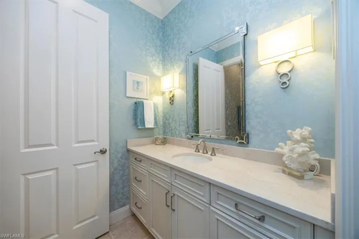 Bathroom with vanity, wallpapered walls, and light tile patterned flooring