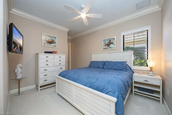 Bedroom with ornamental molding, light colored carpet, and a ceiling fan