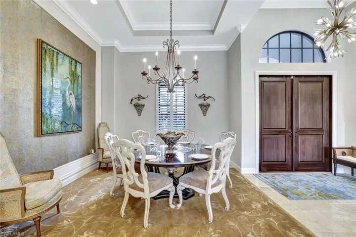 Dining area featuring a chandelier, ornamental molding, and a raised ceiling