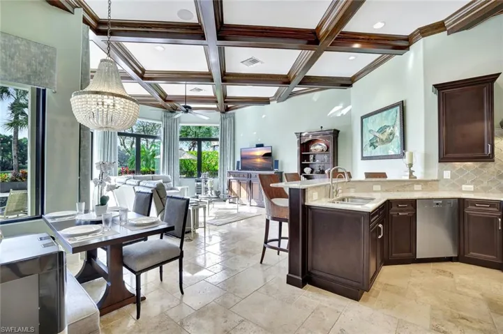 Kitchen featuring dark brown cabinetry, backsplash, light stone countertops, a chandelier, and dishwasher