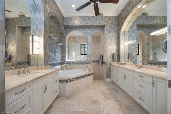 Bathroom with ornamental molding, two vanities, a garden tub, a ceiling fan, and recessed lighting