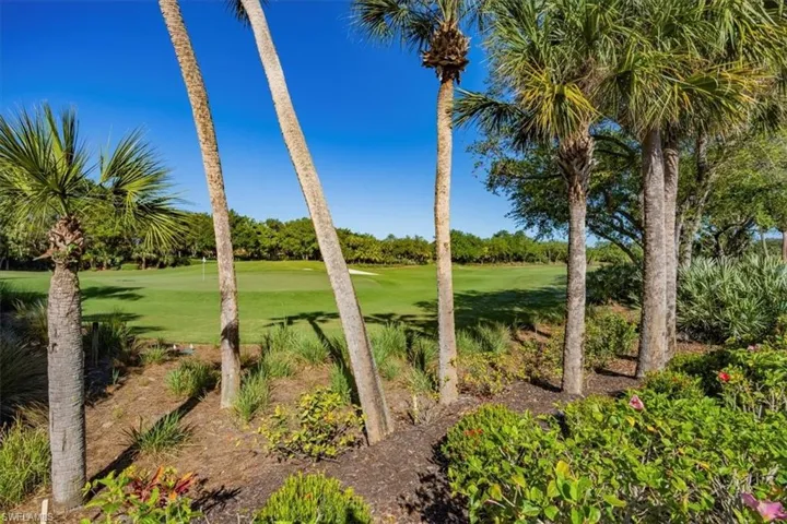 View of green lawn with view of golf course and view of wooded area