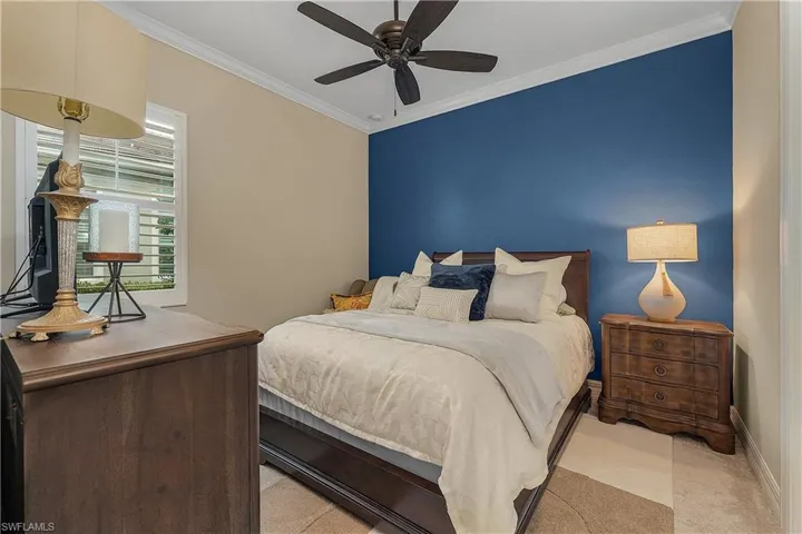 Bedroom with ornamental molding, light carpet, and ceiling fan