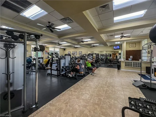 Workout area with ceiling fan, tile patterned floors, and coffered ceiling