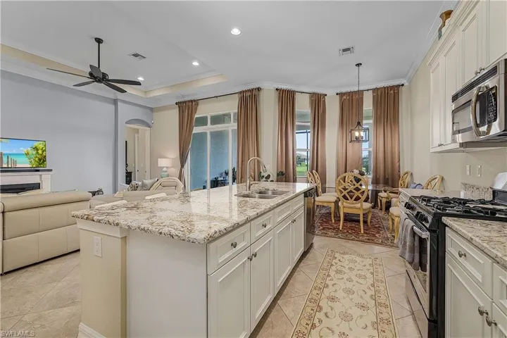 Kitchen featuring a kitchen island with sink, appliances with stainless steel finishes, sink, and white cabinets