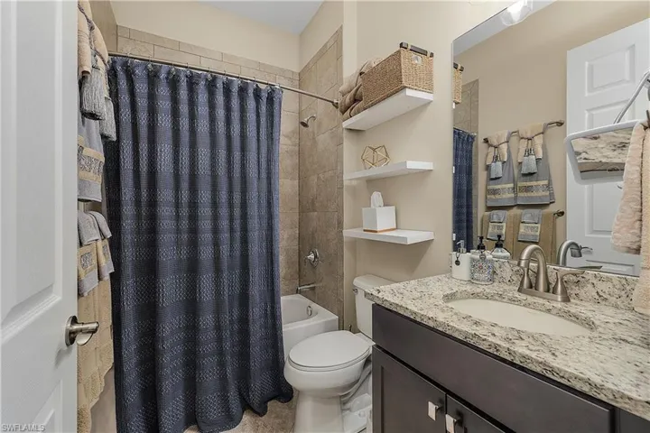 Full bathroom with vanity, toilet, and shower / bath combination with curtain