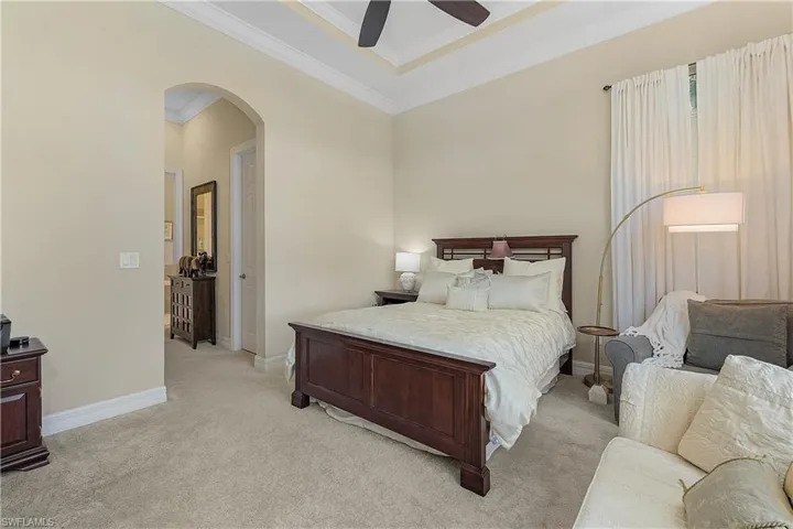 Bedroom featuring light colored carpet, ornamental molding, and ceiling fan