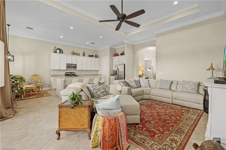 Tiled living room featuring ornamental molding, sink, ceiling fan, and a raised ceiling
