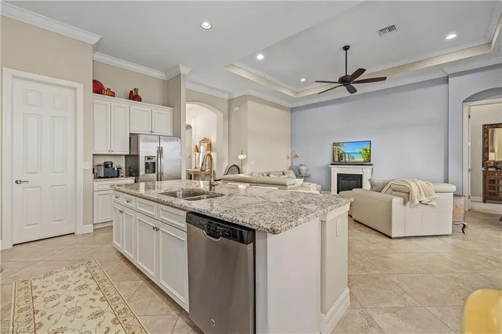Kitchen featuring white cabinetry, ornamental molding, sink, a center island with sink, and appliances with stainless steel finishes