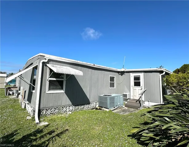Back of house with a lawn and central AC unit