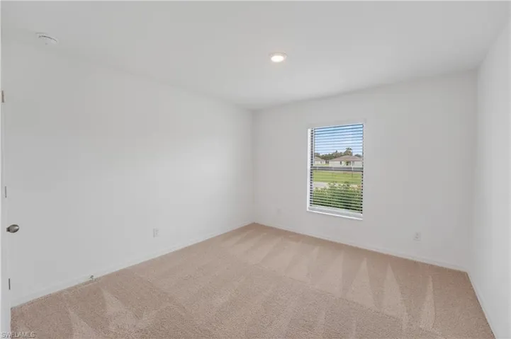 Carpeted room featuring a single window with horizontal blinds, white walls, and a recessed ceiling light