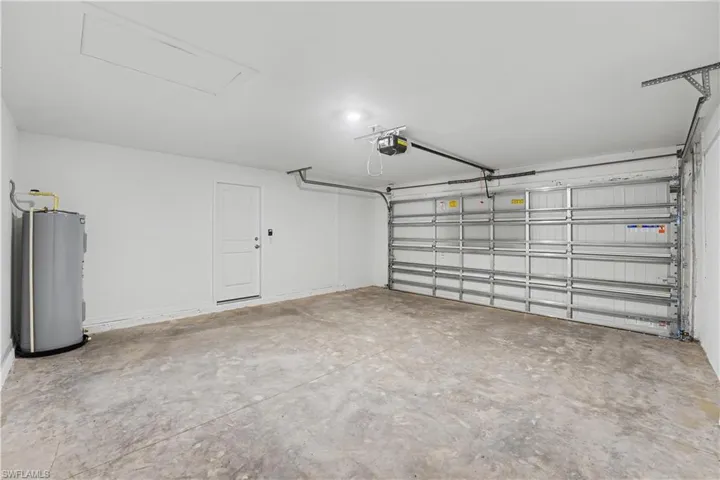 Spacious garage featuring a concrete floor, automatic garage door opener, and a water heater