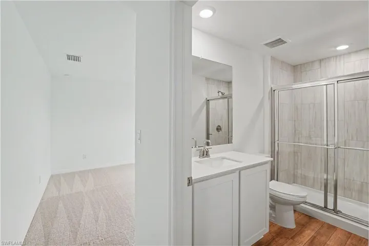 Bathroom featuring a white vanity with an integrated sink, a rectangular mirror, and a glass-enclosed shower with tiled walls