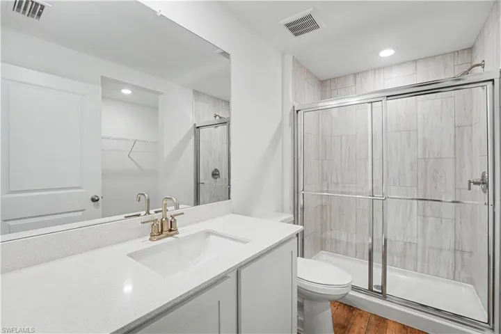 Bathroom featuring a white vanity with an integrated sink and light-toned countertop, a frameless mirror, and brass-tone fixtures