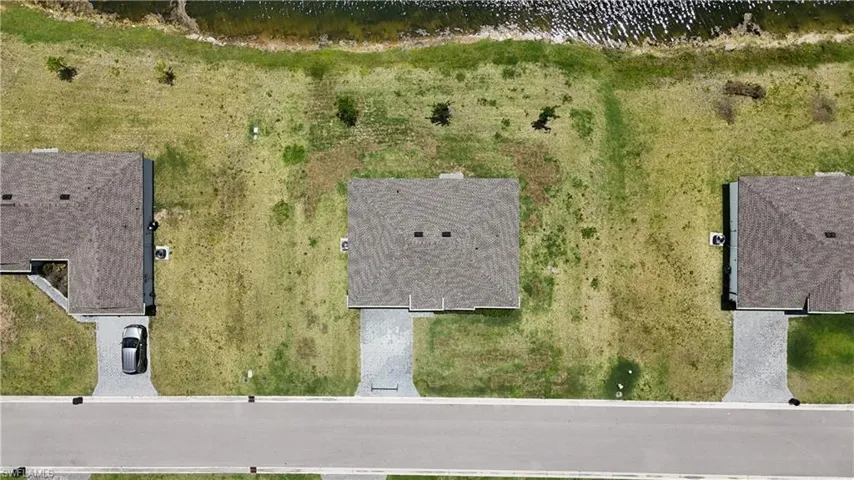 0.29 +/- ac Property featuring water view, a paved driveway, and a verdant lawn extending to a body of water