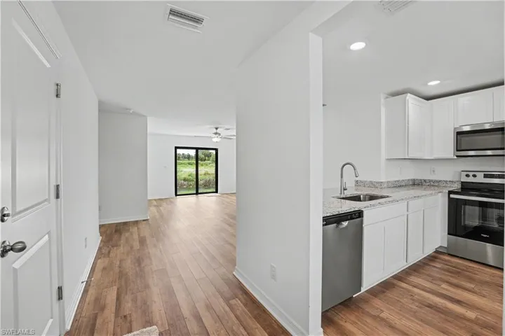 Modern kitchen featuring white cabinetry, light granite countertops, and stainless steel appliances
