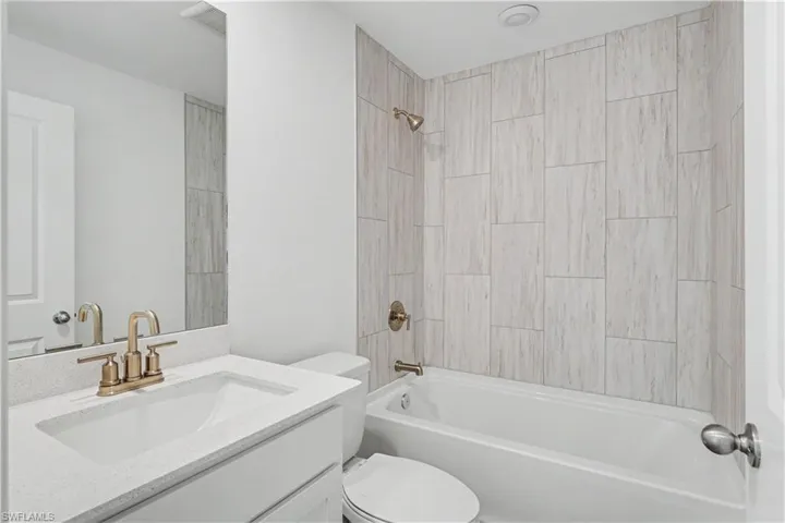Bathroom featuring a single vanity with a white countertop and undermount sink, brass finish faucet, and rectangular mirror