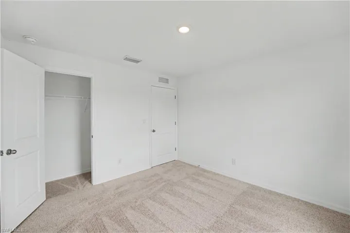 Room featuring textured carpet flooring, white painted walls, and a recessed ceiling light