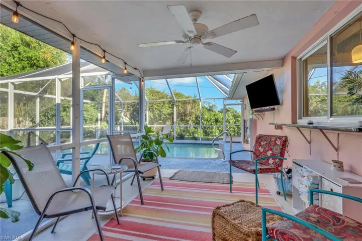Screened-in lanai featuring a ceiling fan, concrete flooring, and an attached pass-through window, overlooking a pool enclosure