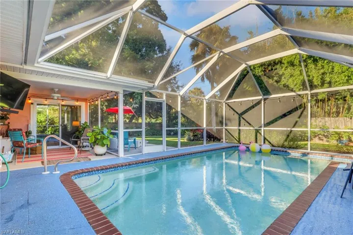 Screen-enclosed pool featuring a tiered entry, brick coping, textured pool deck, and a covered lanai with a ceiling fan