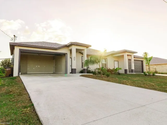 Prairie-style home with stucco siding, a garage, concrete driveway, and a front lawn