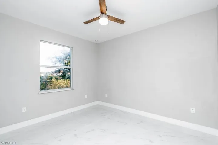 Empty room featuring light marble finish floors and ceiling fan