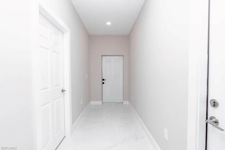 Hallway with light marble finish floors and recessed lighting