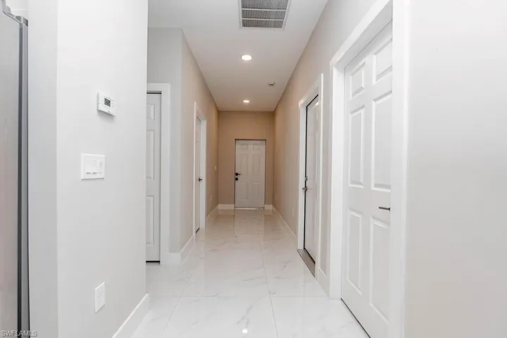Corridor featuring recessed lighting and light marble finish flooring