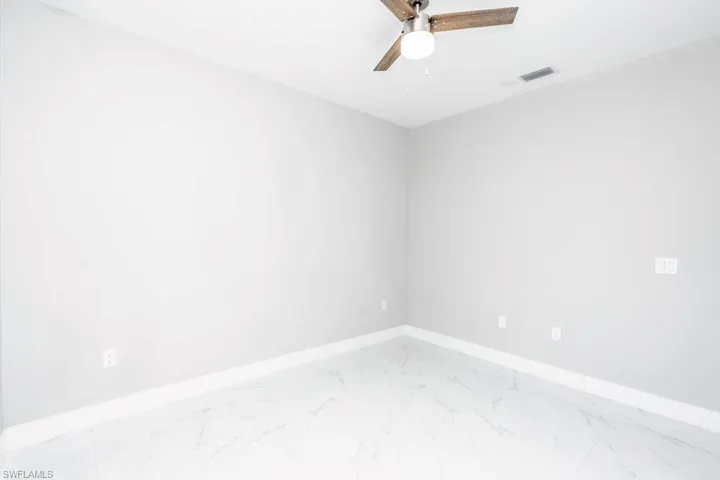 Spare room with marble finish flooring and a ceiling fan