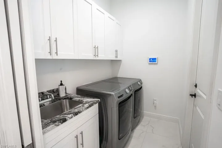 Laundry room featuring washer and dryer, cabinets, sink, and light tile floors