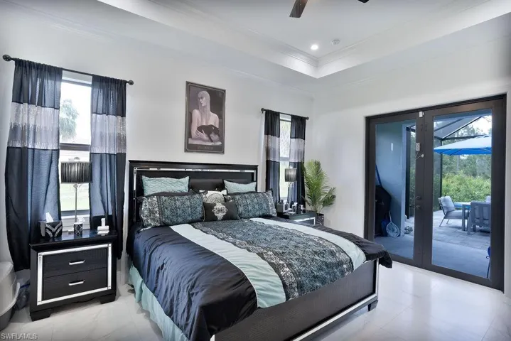Primary bedroom featuring  a light tile floor, ceiling fan, french doors, and access to the patio/pool/ lanai