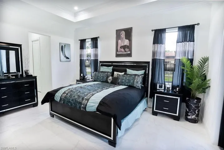 Primary bedroom featuring a tray ceiling and light tile floors