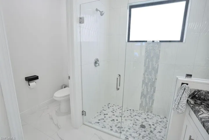 Primary bathroom featuring tile flooring, an enclosed shower, seperate toilet