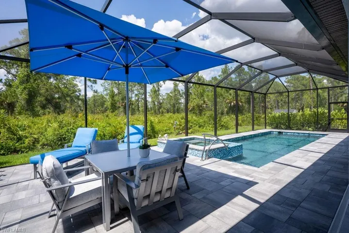 Beautiful backyard view of tiled lanai/patio area with heated saltwater pool/spa