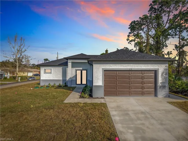 View of front of property featuring a yard and a garage