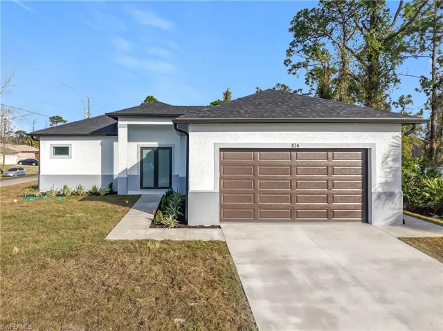 View of front of property with a garage and a front lawn