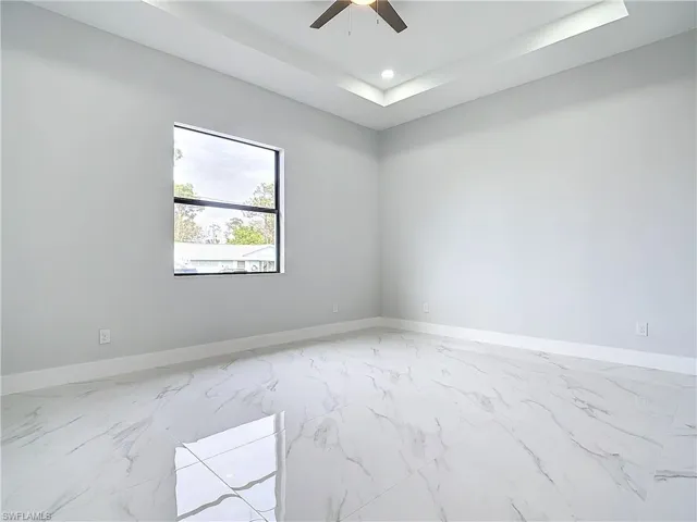 Unfurnished room with a raised ceiling and ceiling fan