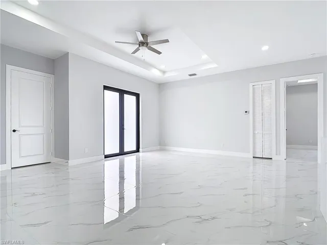 Empty room featuring french doors, ceiling fan, and a raised ceiling