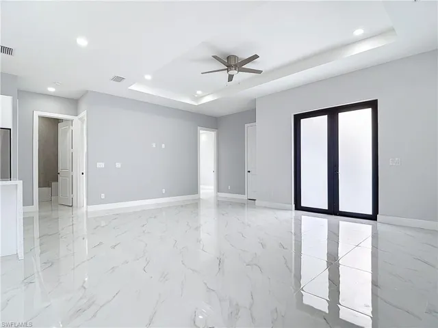 Unfurnished room with french doors, ceiling fan, and a tray ceiling