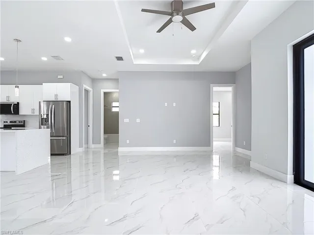 Unfurnished living room featuring a raised ceiling and ceiling fan