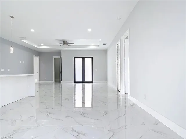 Spare room featuring a raised ceiling, ceiling fan, and french doors