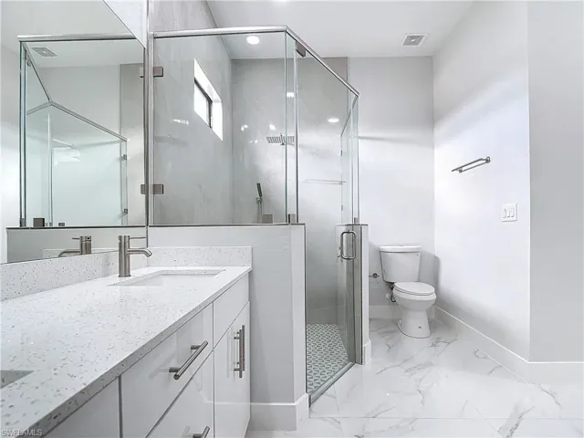Bathroom with vanity, toilet, and a shower with shower door