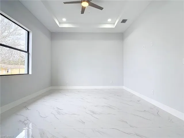 Empty room featuring a raised ceiling and ceiling fan