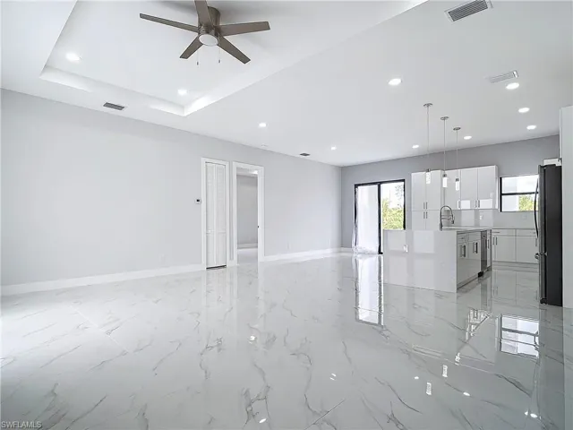 Empty room featuring a raised ceiling, plenty of natural light, sink, and ceiling fan