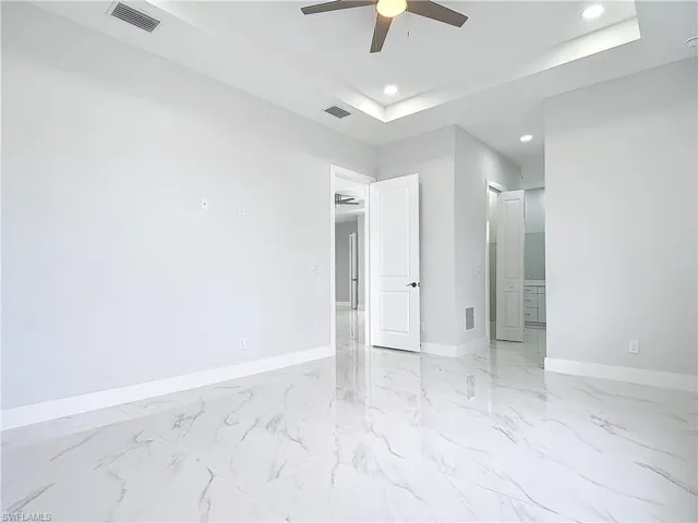 Empty room with ceiling fan and a raised ceiling