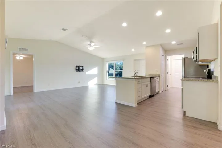 Kitchen with light stone counters, open floor plan, recessed lighting, light wood-style floors, and a peninsula